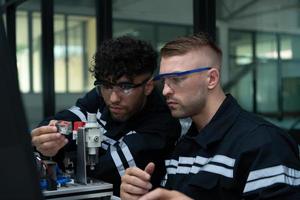 The robotic hand technology teacher is instructing new students on how to use electronic circuit boards and robotic hand commands for a variety of industrial applications. photo