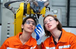 In an electronic parts facility, two female engineers In the plant, inspecting and testing robotic hands used in the production of electronic components. photo