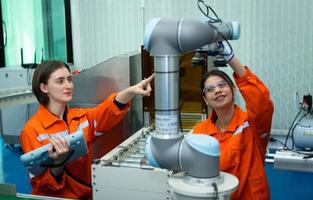In an electronic parts facility, two female engineers In the plant, inspecting and testing robotic hands used in the production of electronic components. photo