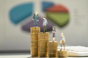 business accounting concept. miniature  toy meeting stand on coins with paper work graph background photo