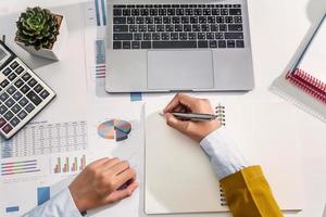 businesswoman working on desk using calculator and laptop analyzing finance accounting photo