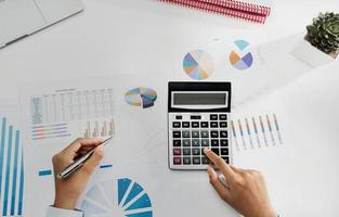 businesswoman working on desk using calculator and laptop analyzing finance accounting in office photo