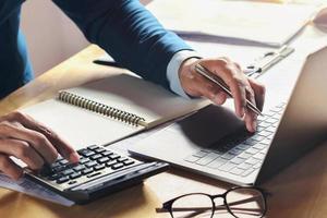businessman working on desk with using calculator and computer in office. concept accounting finance photo