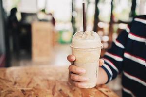 woman hand holding coffee in plastic cup in shop photo