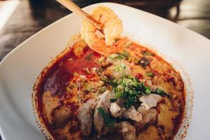 Tom Yum Goong or Spicy prawn soup mixed with meat ball noodles, Thai style and iconic popular taste of Thai foods. photo
