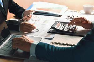 businessman use calculator and computer for  meeting with team accountant on desk in office. finance and accounting concept photo