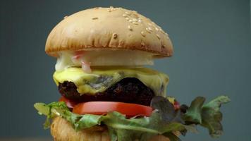 frischer leckerer hausgemachter hamburger mit frischem gemüse, salat, tomate, käse auf einem schneidebrett. Freiraum für Text video