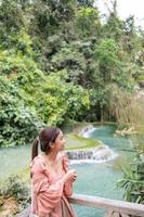 Asian woman standing on the wooden walkway in the Kuang Si Waterfall  Lung Prabang, Laos photo