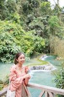 Asian woman standing on the wooden walkway in the Kuang Si Waterfall  Lung Prabang, Laos photo