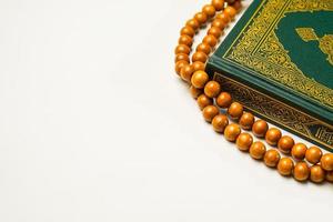 The Holy Al Quran with written arabic calligraphy meaning of Al Quran and rosary beads or tasbih on white background, isolated with copy space. photo
