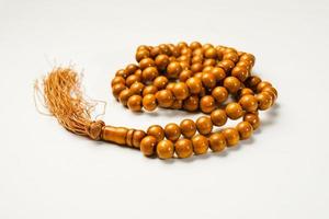 The Holy Al Quran with written arabic calligraphy meaning of Al Quran and rosary beads or tasbih on white background, isolated with copy space. photo