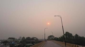 hermosa camara lenta vídeo de un puente y vehículo movimienot. peatonal caminando en un puente pavimento 4k video. escénico ver de el puesta de sol terminado un pequeño puente desde un Moviente vehículo, 4k imágenes. video