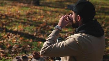 bearded hipster in a cap drinks tea from a bowl outdoors video