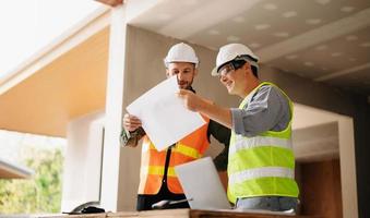Contractor and architect looking at plan, tablet, laptop and talking about working on big project. Building in construction process interior. team work photo