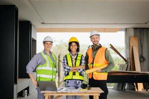 ingenieros son que se discute datos trabajando y ordenador portátil o tableta con arquitectónico proyecto a nuevo construcción sitio en grande proyecto. foto