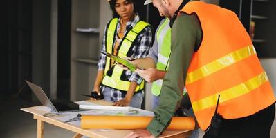 Architect caucasian man and woman working with colleagues mixed race in the construction site. Architecture engineering on big project. Building in construction process interior. photo