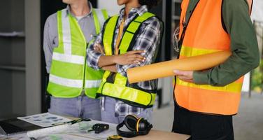 ingenieros son que se discute datos trabajando y ordenador portátil o tableta con arquitectónico proyecto a nuevo construcción sitio en grande proyecto. foto