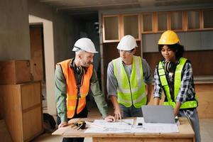 Architect caucasian man and woman working with colleagues mixed race in the construction site. Architecture engineering on big project. Building in construction process interior. photo
