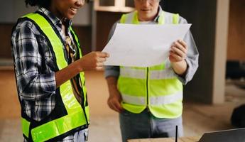 Architect caucasian man and woman working with colleagues mixed race in the construction site. Architecture engineering on big project. Building in construction process interior. photo