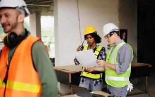 Architect caucasian man and woman working with colleagues mixed race in the construction site. Architecture engineering on big project. Building in construction process interior. photo