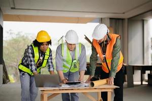 Architect caucasian man and woman working with colleagues mixed race in the construction site. Architecture engineering on big project. Building in construction process interior. photo