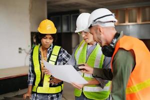 Architect caucasian man and woman working with colleagues mixed race in the construction site. Architecture engineering on big project. Building in construction process interior. photo