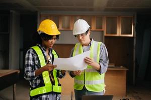 Architect caucasian man and woman working with colleagues mixed race in the construction site. Architecture engineering on big project. Building in construction process interior. photo