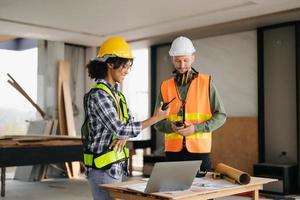 Contractor and architect looking at plan, tablet, laptop and talking about working on big project. Building in construction process interior. team work photo