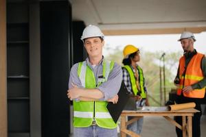 Contractor and architect looking at plan, tablet, laptop and talking about working on big project. Building in construction process interior. team work photo