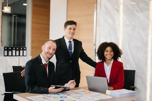 empresarios felices mientras colaboran en un nuevo proyecto en una oficina. grupo de diversos empresarios que usan una computadora portátil y una tableta en la oficina. foto