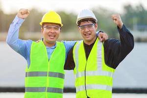 dos profesional ingenieros que se discute y alegre en éxito durante trabajando a el paneles a solar energía en boya flotante.eco tecnología para eléctrico poder en industria. foto