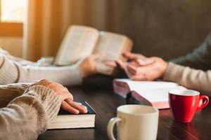 Small group of asian people praying worship believe. Teams of friends worship together before studying Holy bible. family praying together in church. Small group learning with prayer concept. photo