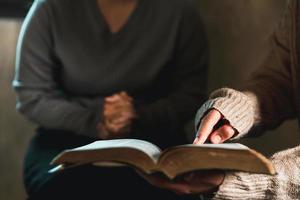 Small group of asian people praying worship believe. Teams of friends worship together before studying Holy bible. family praying together in church. Small group learning with prayer concept. photo