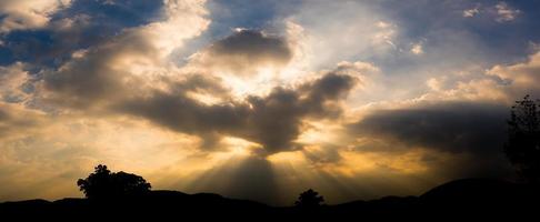 puesta de sol panorámica con nubes en el cielo crepuscular con silueta de montaña foto