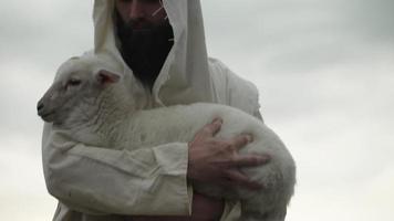 een liefhebbend herder Holding een baby schaap, lam in zijn armen video