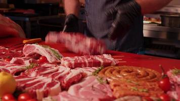 chef handen het werpen een brok van rauw lam Aan de rood tafel naar karbonade het in stukken voor steak. video