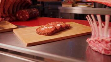 Slices of homemade sausage on a wooden cutiing board along with pork. video