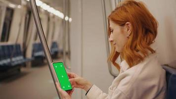 turista donna seduta nel la metropolitana e pergamene il verde schermo Telefono su il treno. video