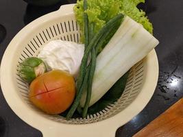 Close up photo of salad on the white basket, tomato, eggplant and cabbage. The photo is suitable to use for vegan food background, poster and food content.