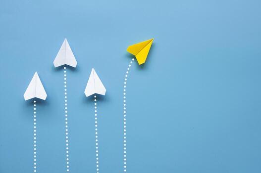 parte superior ver de papel avión - amarillo papel avión origami volador a un diferente dirección dejando otro blanco aviones en azul antecedentes con personalizable espacio para texto o ideas foto