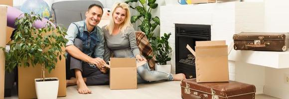 Young couple on the floor after moving into a new home with boxes around them. photo