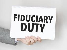 man's hand holding paper sheet with fiduciary duty words photo