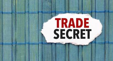 trade secret word on torn paper with blue wooden background photo
