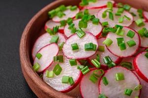 Delicious fresh salad of sliced radishes with green onions, salt and olive oil photo