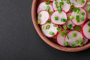 Delicious fresh salad of sliced radishes with green onions, salt and olive oil photo