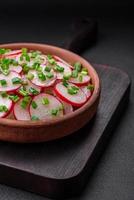 Delicious fresh salad of sliced radishes with green onions, salt and olive oil photo