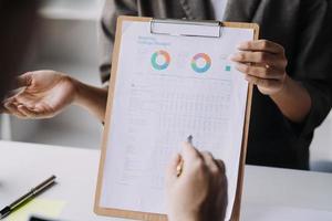 Financial analysts analyze business financial reports on a digital tablet planning investment project during a discussion at a meeting of corporate showing the results of their successful teamwork. photo