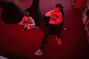 Two boys gamers play gamepad video game console in red gaming room. photo