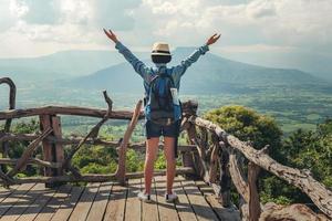 mujer viajero con mochila disfrutando ver y contento libertad a montañas foto