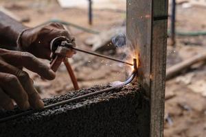 de cerca mano soldadura metal en construcción sitio foto